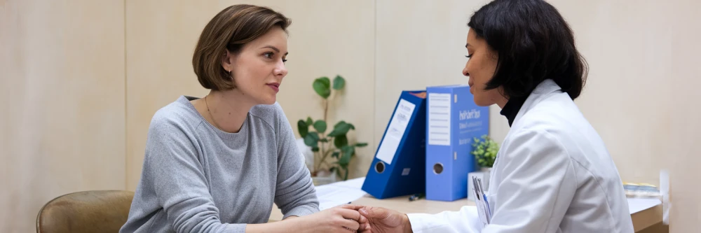 Image d'une femme en consultation avec un professionnel de santé, discutant des solutions thérapeutiques, symbolisant l'importance d'un suivi médical rigoureux pour l'utilisation du CBD dans les traitements anticancéreux.