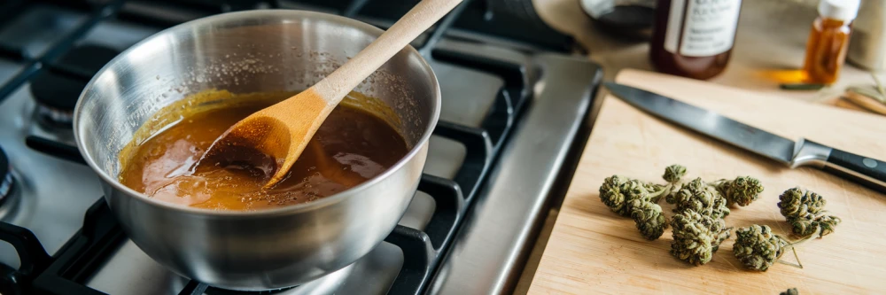 Illustration présentant une casserole sur une cuisinière avec un mélange de sirop en train de mijoter, accompagné d'une cuillère en bois pour remuer, et des fleurs de CBD prêtes à être incorporées sur le côté.